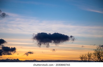 Single Dark Cloud Floating Over Horizon At Sunset