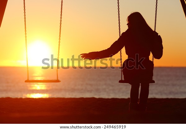 Single or divorced woman alone missing a\
boyfriend while swinging on the beach at\
sunset