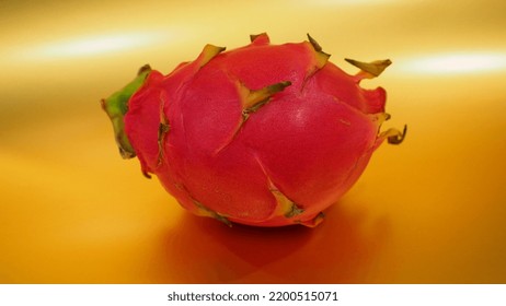 Single Dragon Fruit Against A Gold Background