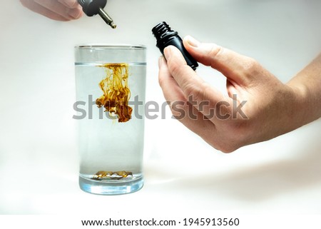 A single drop of concentrated Colloidal Silver being diluted in a glass of water. 