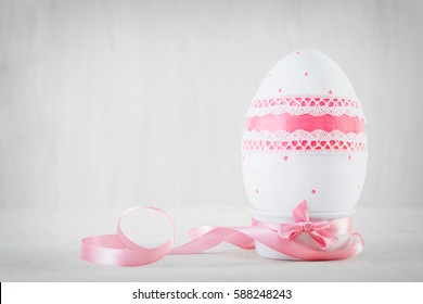Single easter handmade egg on wooden white table. Decoupage art, pastel tone