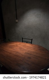 A Single Empty Chair With A Wooden Table Below Spotlight. Illustration Picture Of Interrogation Room. Empty Chair Feels Like Horror Movie Background.