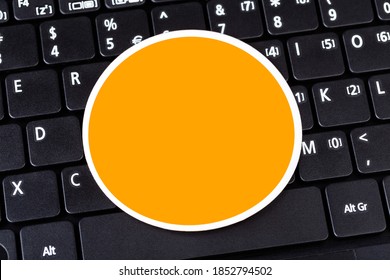 Single Empty Orange Circle Label Logo Space, Round Symbol Blank Sticker Laying On Black Modern Pc Laptop Netbook Computer Keyboard, Closeup, Copy Space. Simple Technology Branding Mockup, Template