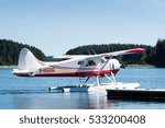 single engine float plane leaving the dock under blue sky in alaska