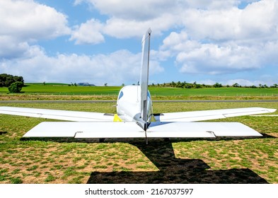 Single engine ultralight aircraft waiting to take off at the aerodrome with field and blue sky background
