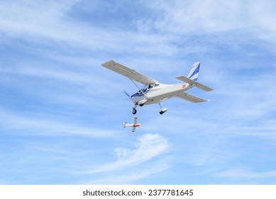 Single engine ultralight plane flying in the blue sky with white clouds