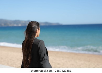 Single executive relaxing contemplating ocean sitting on the beach