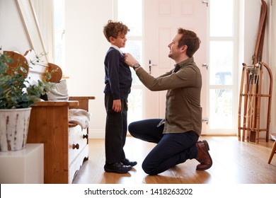 Single Father At Home Getting Son Wearing Uniform Ready For First Day Of School