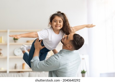 Single father middle-eastern man having fun with his happy little daughter at home, loving dad lifting up his female kid, enjoying time together, copy space. Fatherhood, parenthood concept