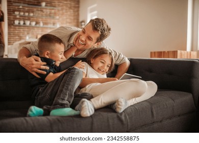 Single father playing with his kids on the couch in the living room at home - Powered by Shutterstock