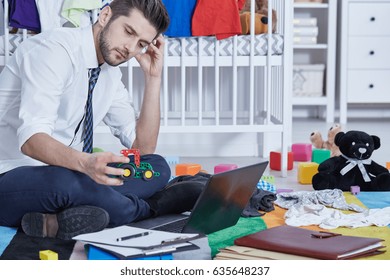 Single father sitting in messy room and trying to work