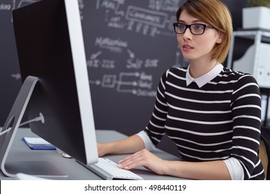 Single Female Computer Scientist In Eyeglasses And Short Hair Seated At Desk In Office