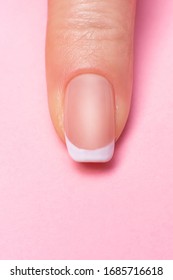 single female finger with a beautiful manicure on a pink background, close-up. clean healthy fingernails. copy space. place for text and logo.
