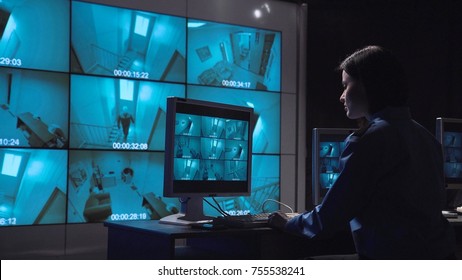 Single female security person monitoring closed circuit surveillance from multiple cameras in various rooms of a building informs on the radio to check the person who moves inside the room. - Powered by Shutterstock