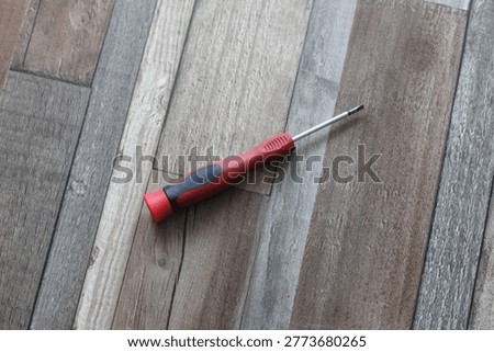 A single flathead screwdriver with a red and black handle
