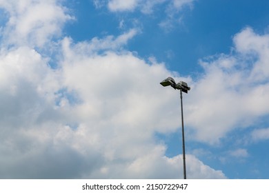 Single Floodlight Isolated Against A Blue Sky With Clouds