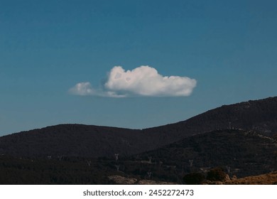 Single Fluffy Cloud Floating Above Mountainous Horizon