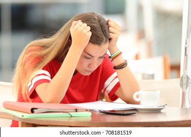 Single frustrated student girl trying to understand notes sitting in a bar