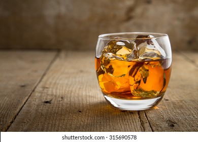 Single Glass Of Whisky Bourbon On The Rocks Golden On Old Rustic Wooden Surface Open Space