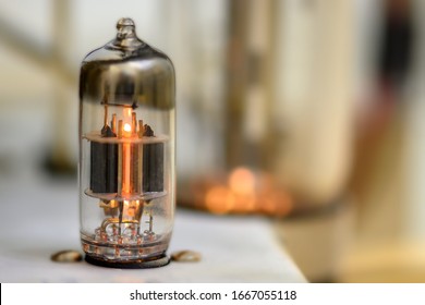 A single glowing vacuum tube. Other tube blowing in the background but outside the shallow depth of field.