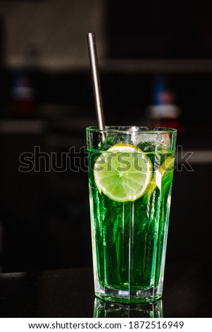 Single green cocktail with lemon as garnish. Dark background so its easy to cut and use on other dark backgrounds