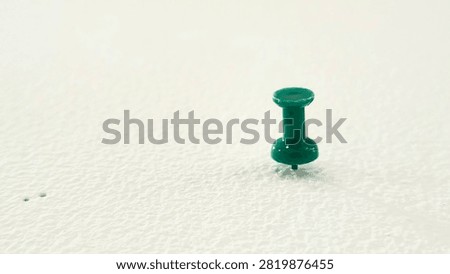 Single Green Push Pin Plastic Thumb Tack Stuck on White Textured Surface with Copy Space