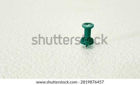 Single Green Push Pin Plastic Thumb Tack Stuck on White Textured Surface with Copy Space