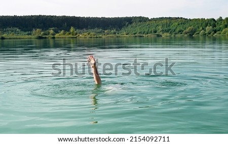 Single hand of drowning man in water asking for help.