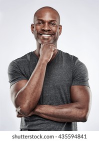 Single Handsome Fit Black Man With Shaved Head, Folded Arms And Hand On Chin While Smiling