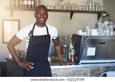 Single handsome young confident male coffee house owner with white shirt and black apron at counter with hand on hip ストックフォト © 