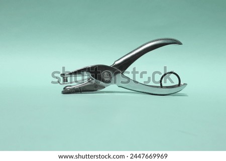 Single Hole Puncher Machine isolated on green paper background. It is made of steel. Office Stationary