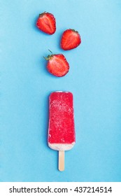 Single Homemade Popsicle With Strawberry Halves On A Blue Background. Top View With Copyspace