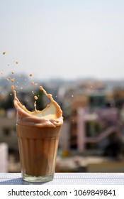 Single India Half Chai (tea) Splash With City Background In Natural Light