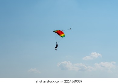 A Single Isolated Paratrooper On A Blue Sky In The Air Flowing On The Cloudless Blue Sky On A Colorful Parachute, Parachutist, Extreme Sports In The Sky, Adrenaline Sports Bird Eye