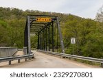 A single lane metal bridge in the woods in Titusville, Pennsylvania, USA on a sunny spring day