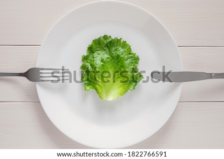 single lettuce leaf on the plate with fork and knife, detox mono diet for weight loss