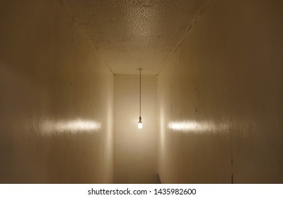 A Single Light Bulb Hanging From A Cable, Showing A Bobble Texture To The Ceiling With A Poor Wall Papered Reflection. 