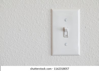 Single light switch on a white wall on