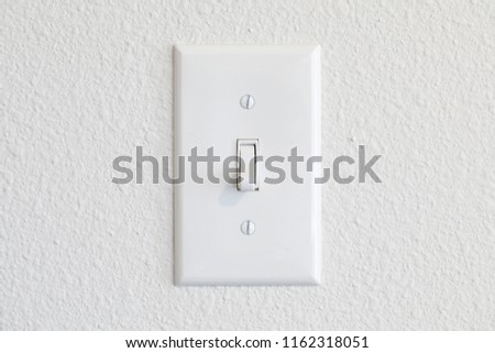 Single light switch on a white wall off