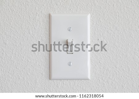 Single light switch on a white wall on