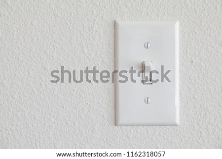 Single light switch on a white wall on