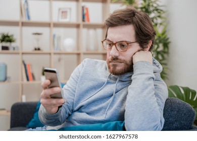 Single lonesome man checking mobile phone on the couch - Powered by Shutterstock