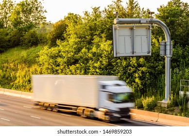 Single Lorry Truck On Uk Motorway Road Under Information Display At Sunset