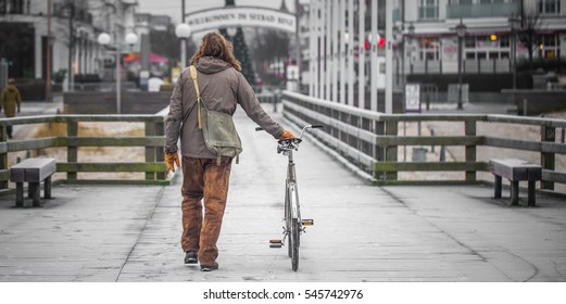a single man dressed in old clothes on the embankment with the bike