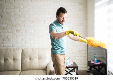 Single Man Dusting His Furniture To Keep The Dust Away From Them And Have A Clean House