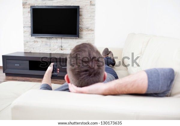 ソファに一人の男がテレビを見 チャンネルを変える の写真素材 今すぐ編集