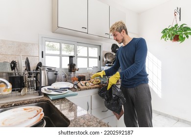 Single man picking up rubbish from his messy kitchen in the morning. Copy space - Powered by Shutterstock