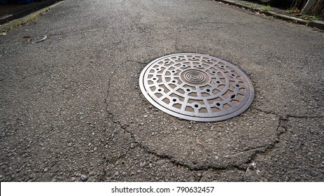 a single manhole cover on an empty japanese road