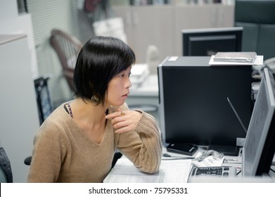 Single Mature Asian Woman Working In Office And Looking At Computer Screen.