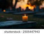 A single, melting candle placed on a cemetery stone, set against the backdrop of a vibrant sunset